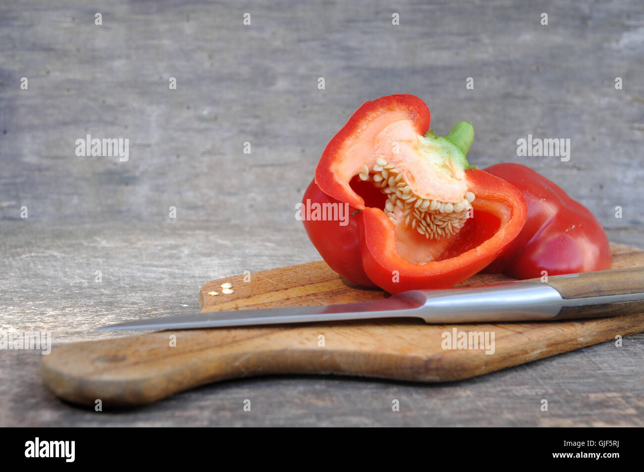 red pepper cut in half on board with knife Stock Photo