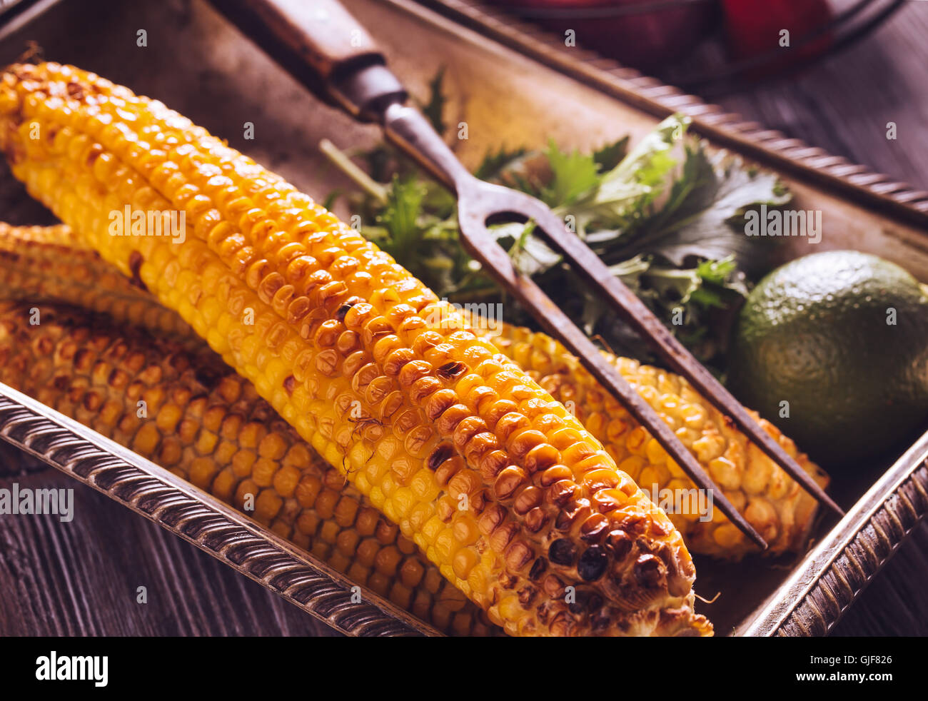 Baked corn in vintage tray with lime Stock Photo