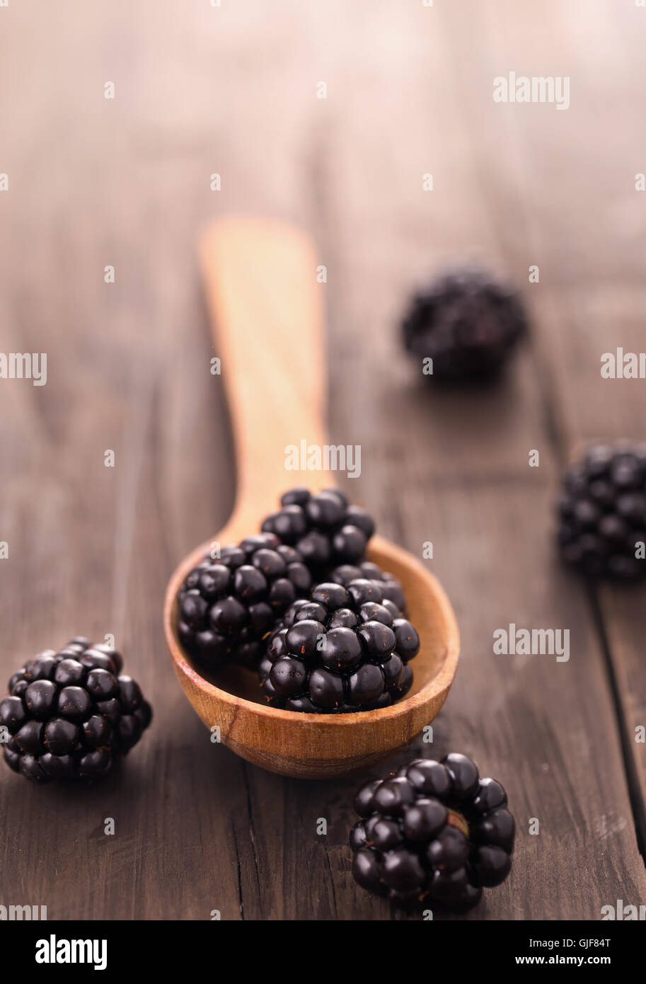 Blackberries with spoon on wooden background Stock Photo