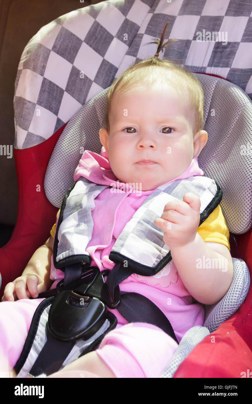 little newborn baby girl rests in the car seat Stock Photo