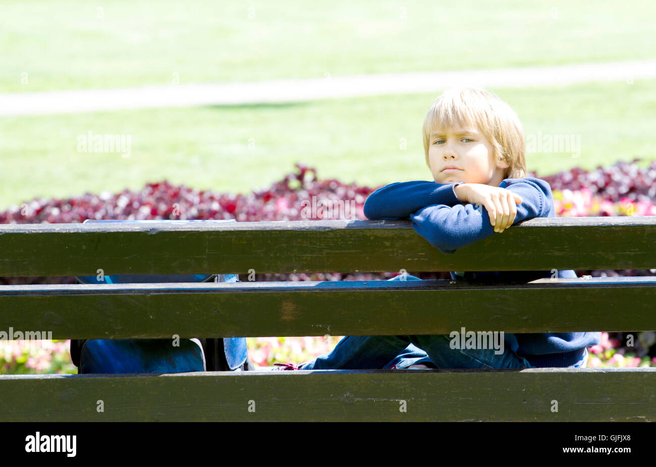 Little boy sitting on bench in the park after the school Stock Photo ...