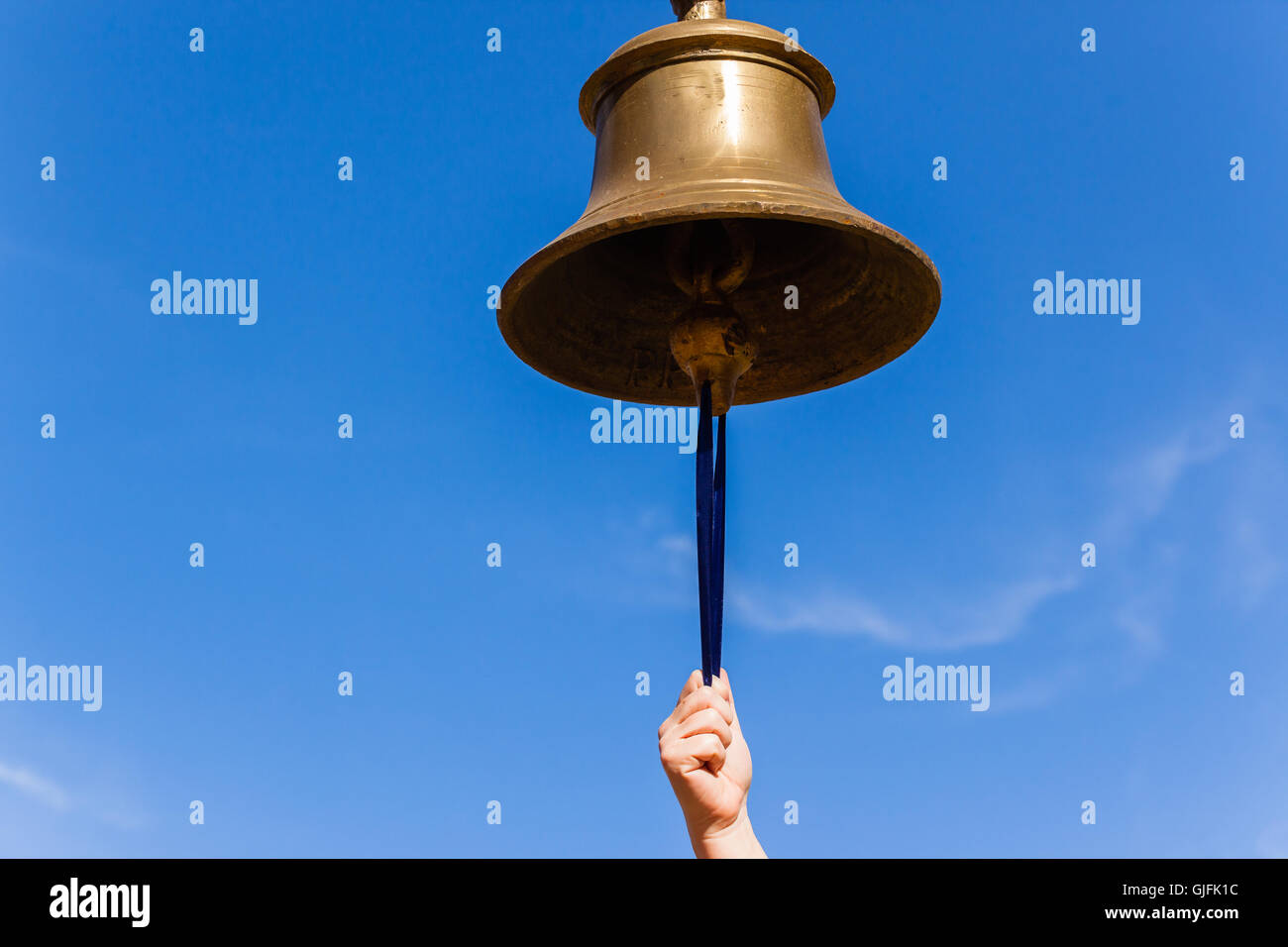 Bell brass with hand closeup against blue sky Stock Photo Alamy