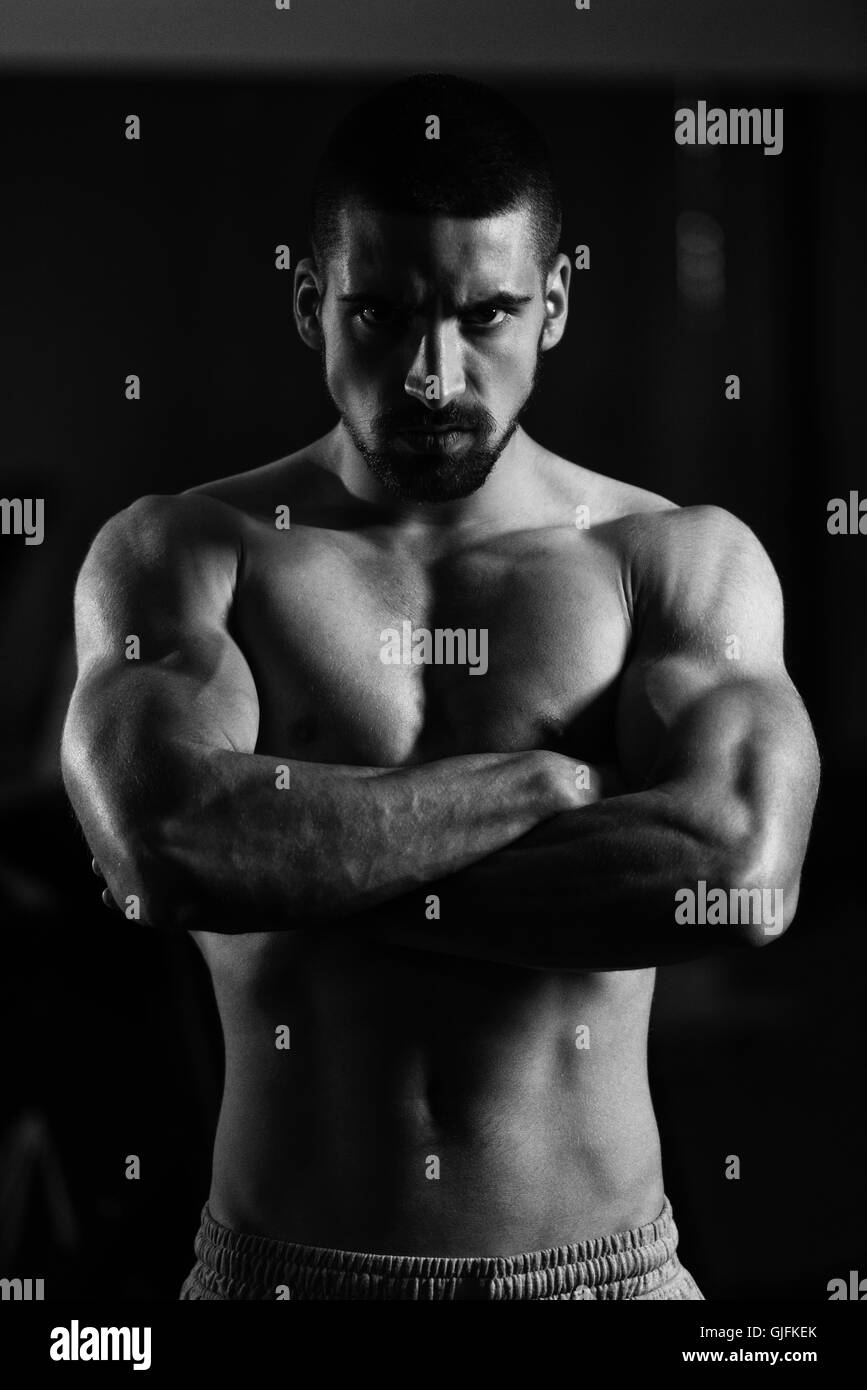 Young Man Standing Strong In The Gym And Flexing Muscles - Muscular Athletic  Bodybuilder Fitness Model Posing After Exercises Stock Photo - Alamy