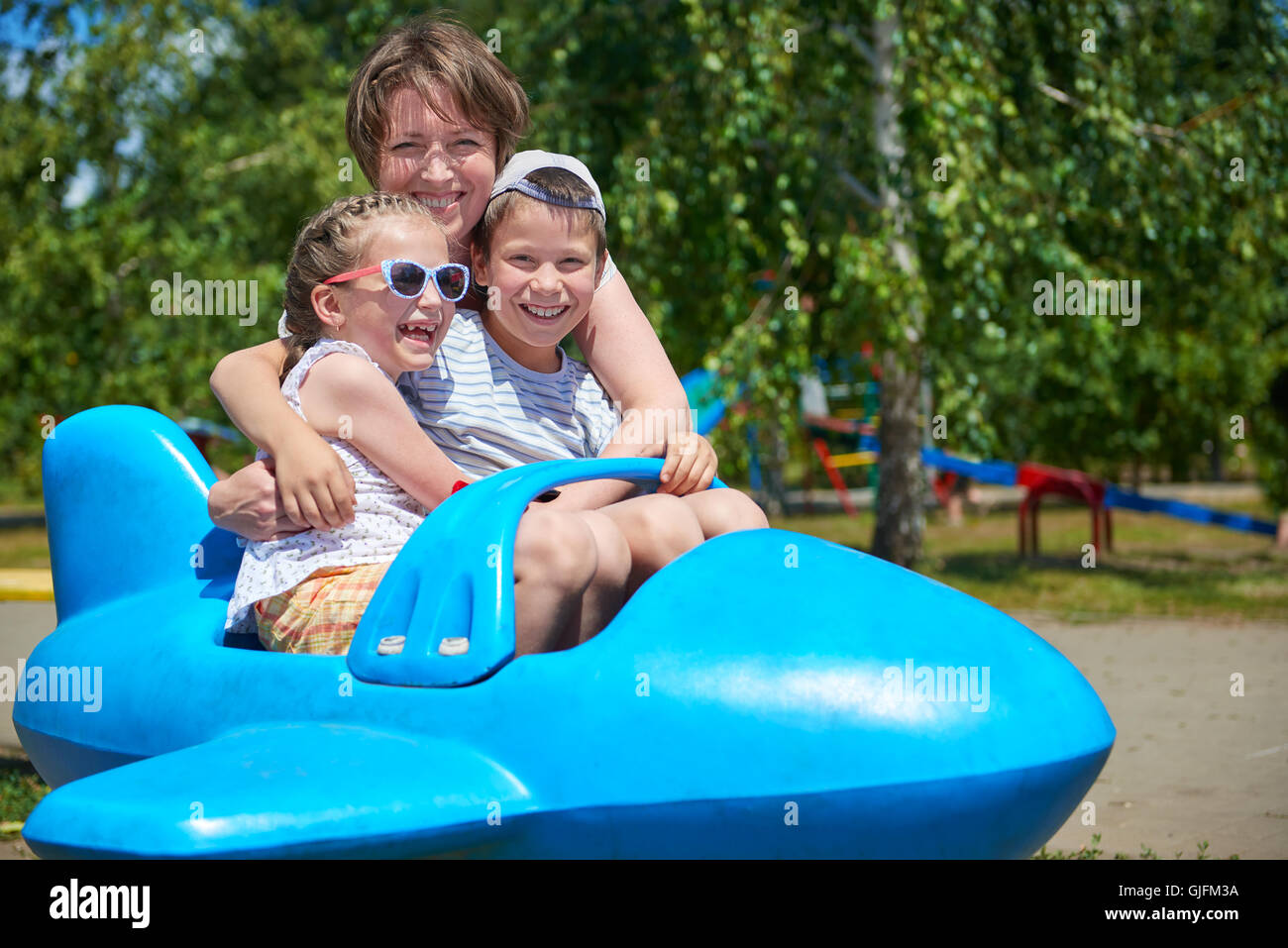 child and woman fly on blue airplane attraction in city park, happy family, summer vacation concept Stock Photo