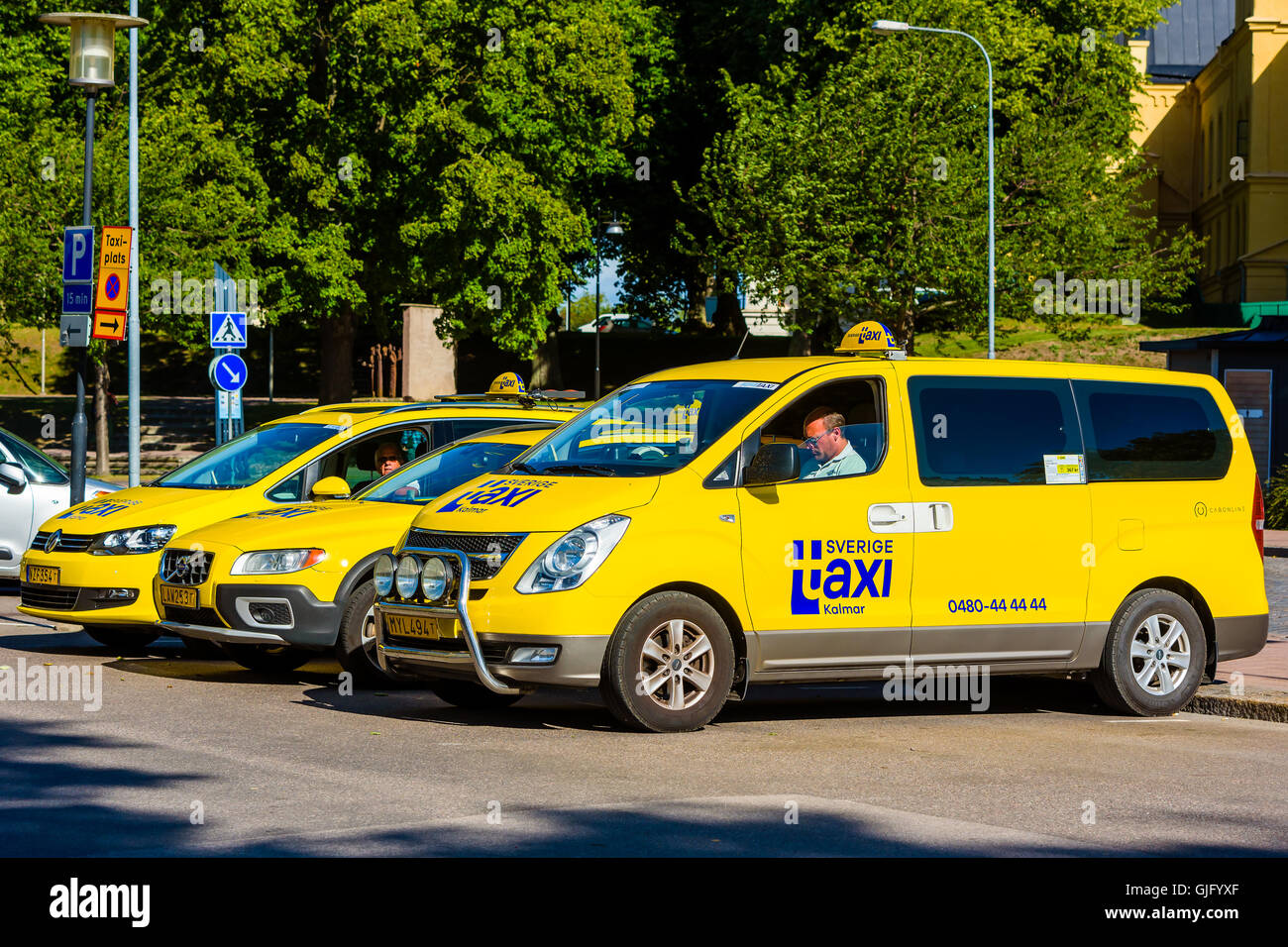 Kalmar, Sweden - August 10, 2016: Three yellow cab or taxi cars waiting for passengers. Sverige Taxi logo on cars. Front most ca Stock Photo