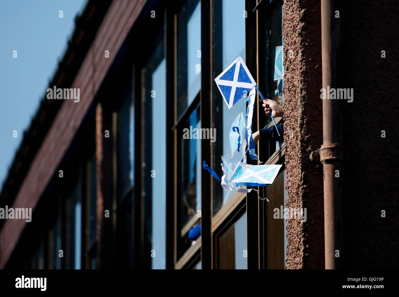 A pupil waves a Saltire flag from a classroom window during First Minister Nicola Sturgeon's visit to Burnfoot Community School, Hawick, to announce funding to raise educational attainment in deprived areas. Stock Photo