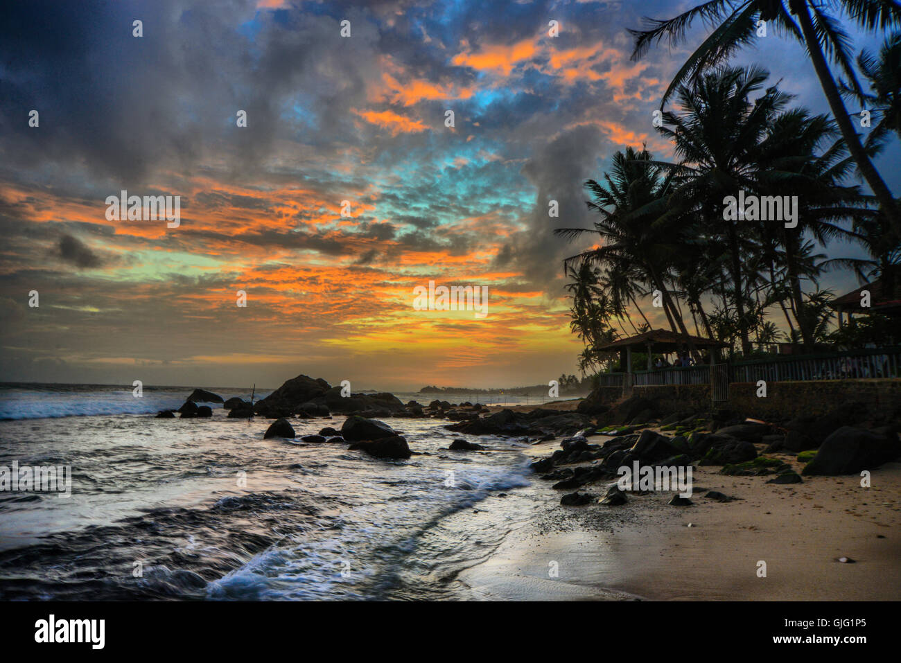 Waves breaking on rocks on a tropical beach at sunset Stock Photo