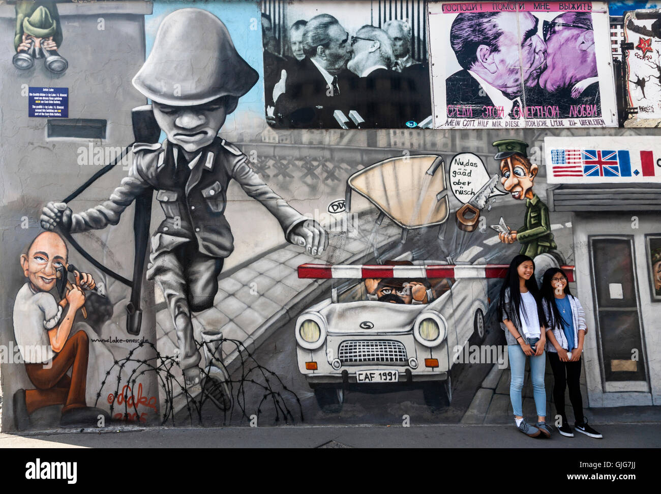 Tourists posing by the mural on the East Side Gallery Store, Friedrichshain, Berlin, Germany. Stock Photo