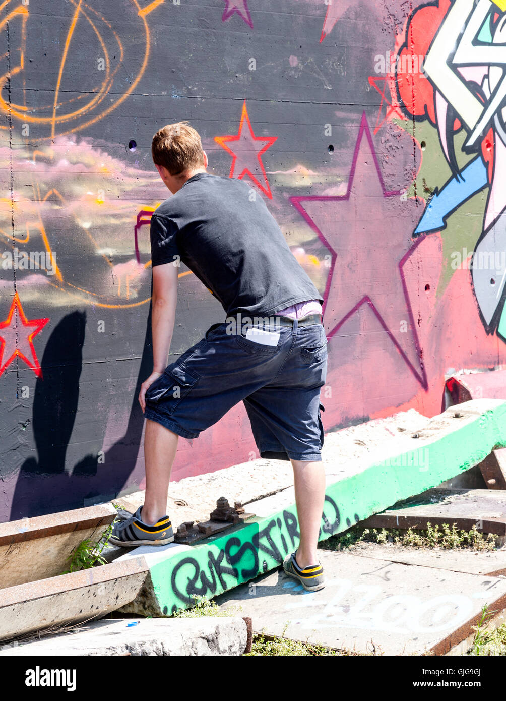 Graffiti artist hard at work painting an old wall, Friedrichshain, Berlin, Germany. Stock Photo