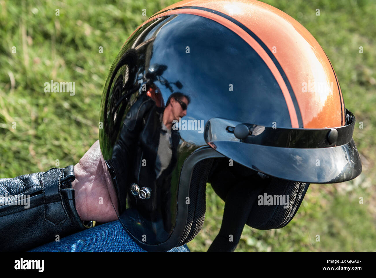 Motorbiker holding retro motorbike helmet with reflection of biker