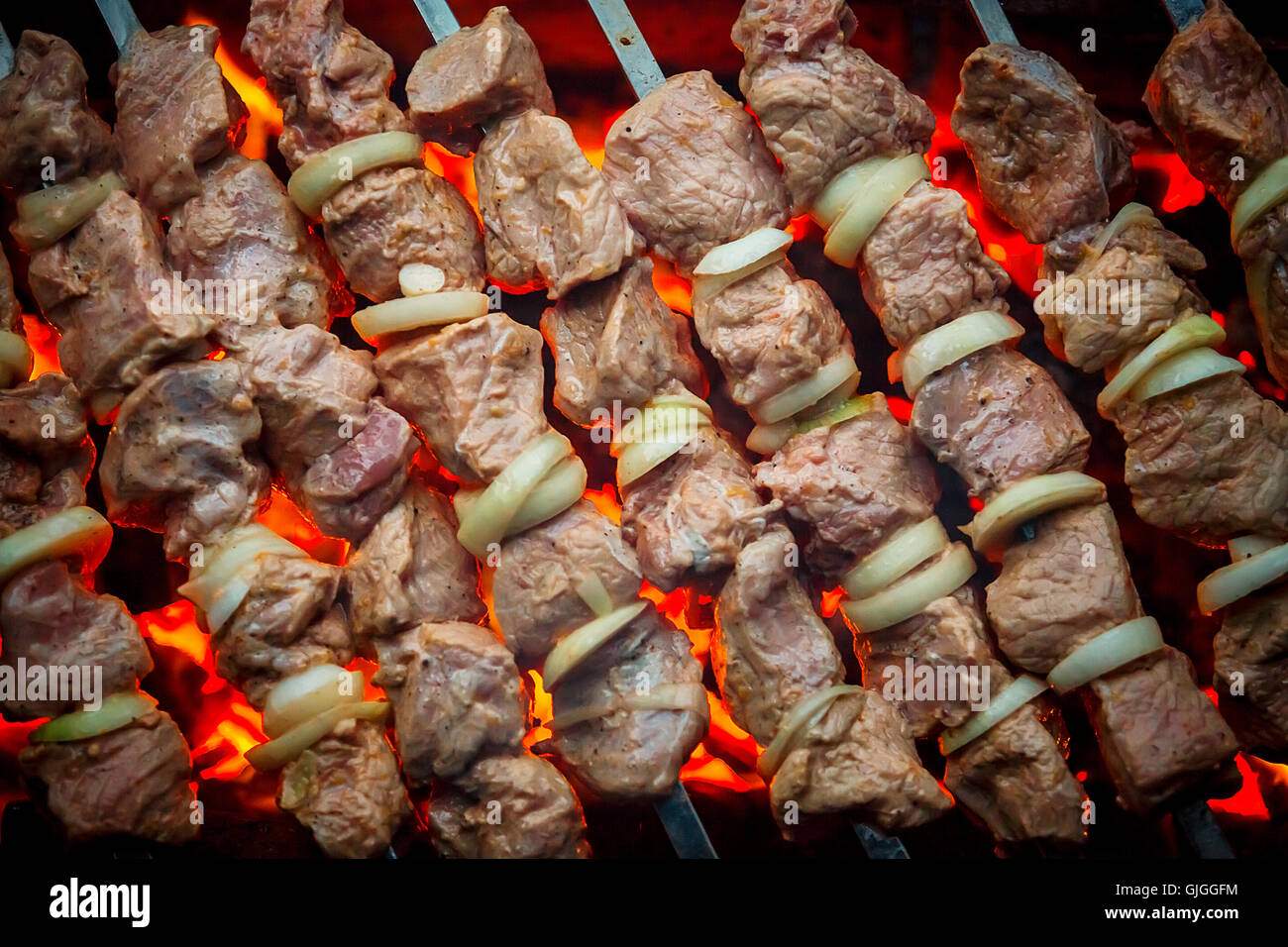 Barbecue pork kebabs on the hot grill closeup. Flames of fire and coals in the background Stock