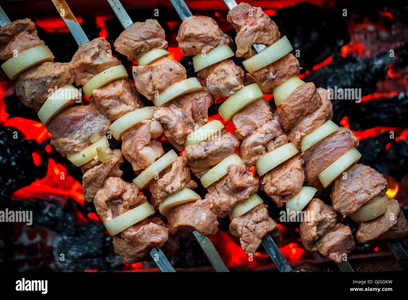 Barbecue pork kebabs on the hot grill closeup. Flames of fire and coals in the background Stock