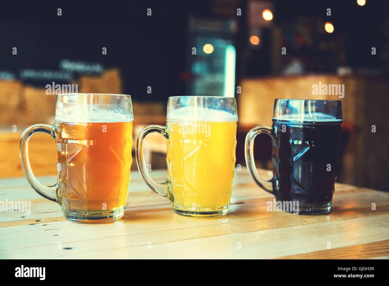 Beautiful background of the Oktoberfest. Glasses of cold fresh white, light and dark beer on the wooden bar counter in the pub. Stock Photo