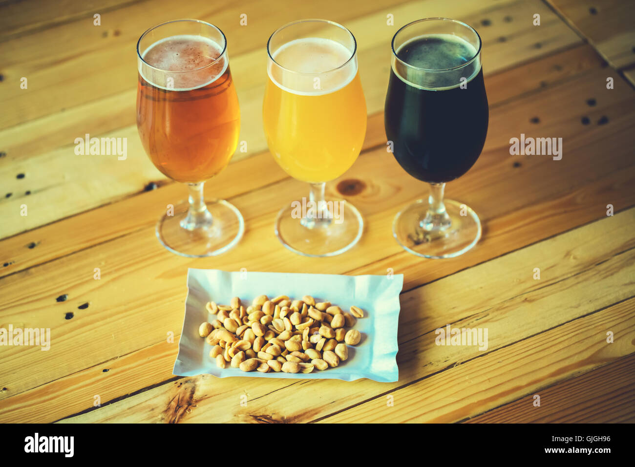 Beautiful background of the Oktoberfest. Glasses of cold fresh white, light and dark beer with peanut nuts on the wooden bar cou Stock Photo