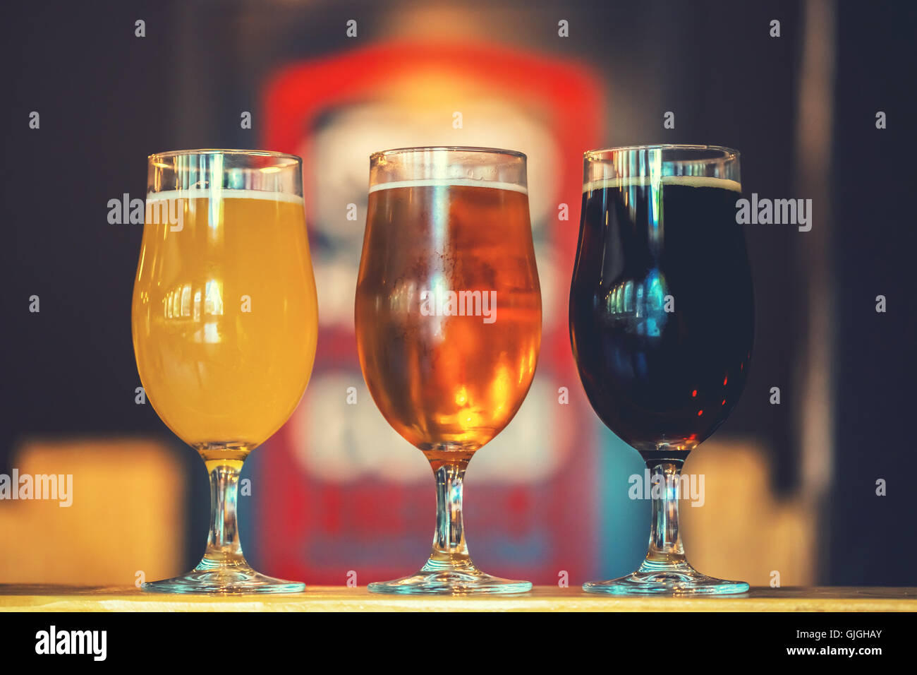 Beautiful background of the Oktoberfest. Glasses of cold fresh white, light and dark beer on the wooden bar counter in the pub. Stock Photo