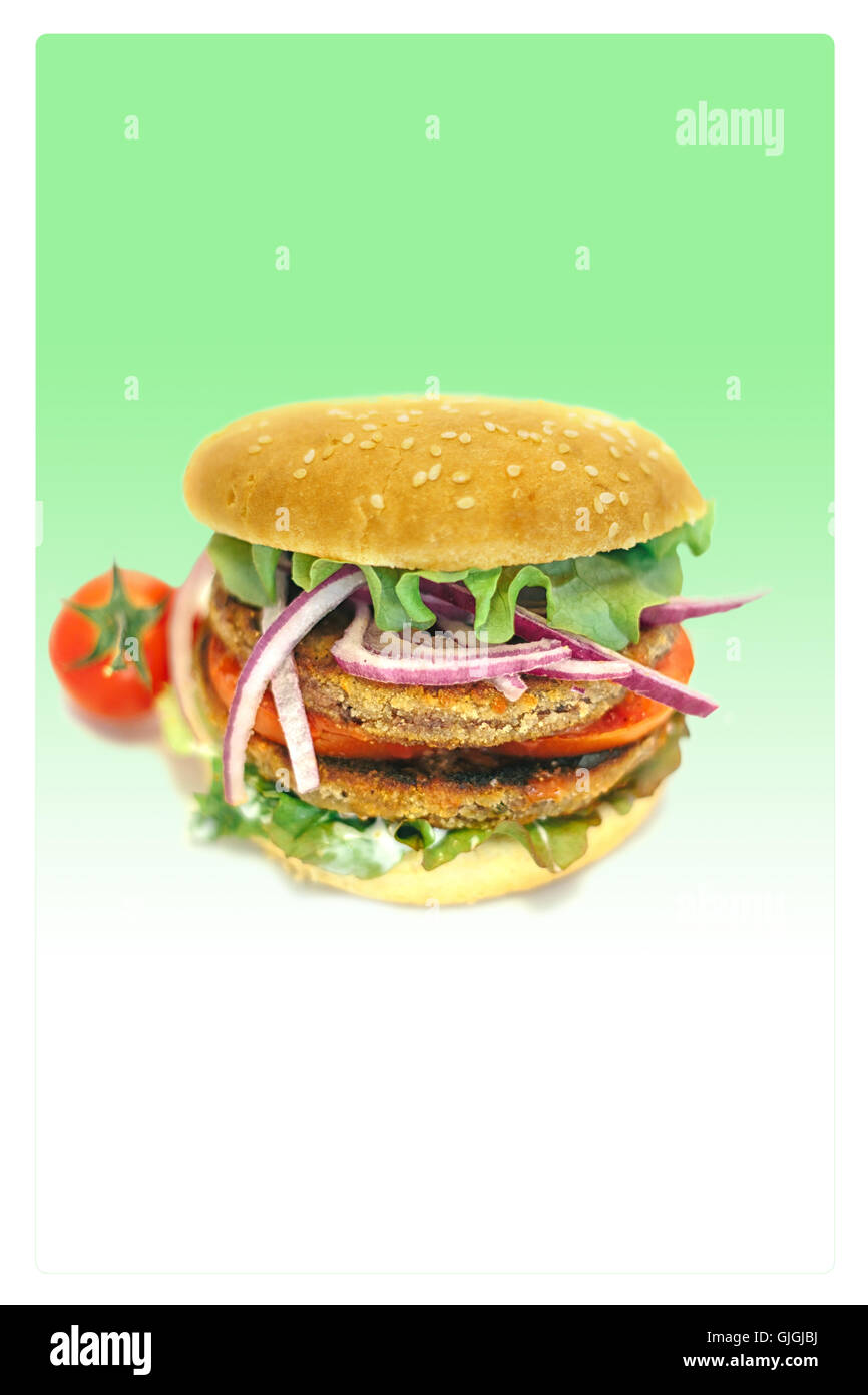 vegetarian hamburger with lettuce, tomato, onion and bun in green background Stock Photo