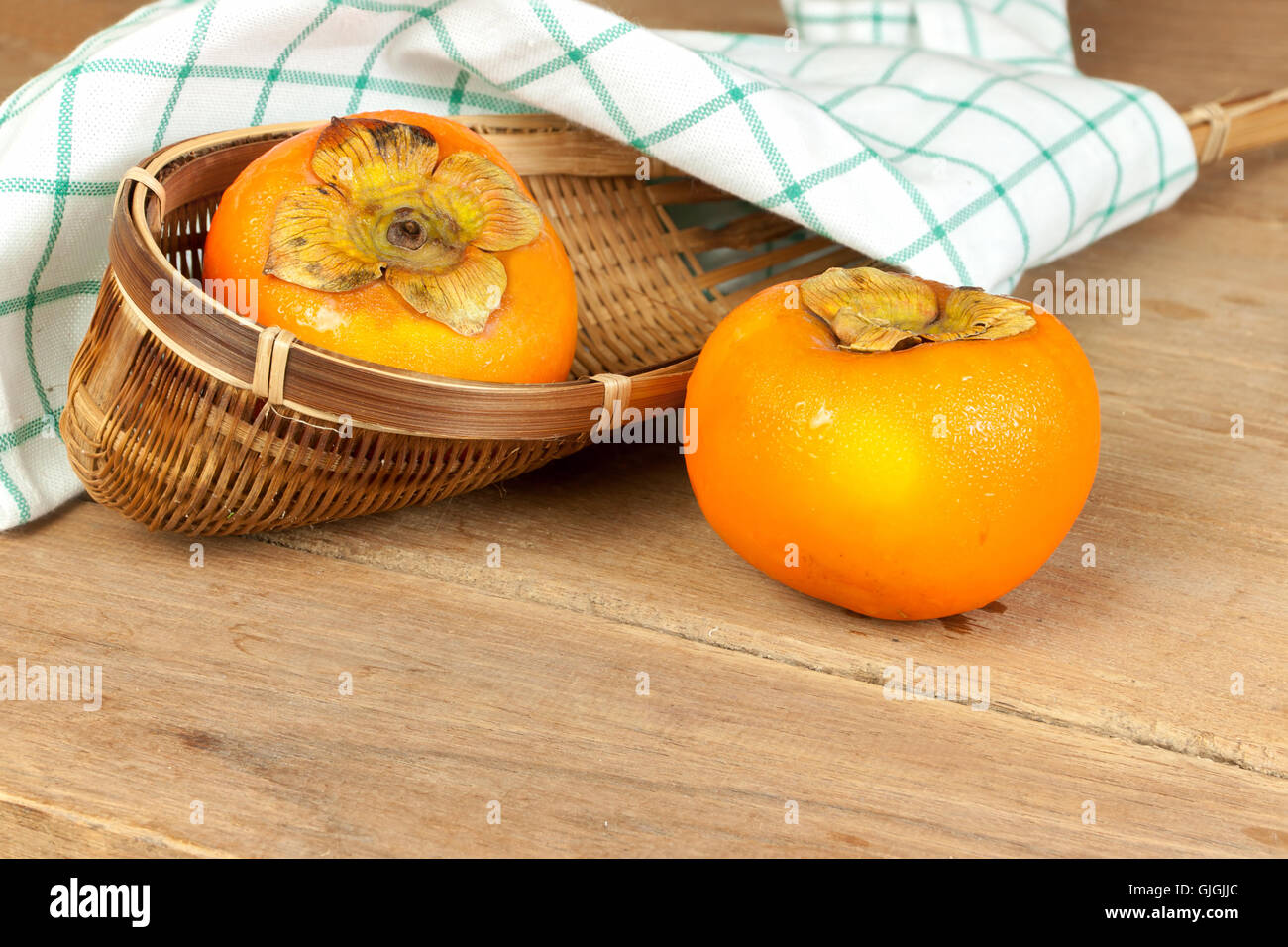 Persimmon yellow color ripe fruits on wood table Stock Photo