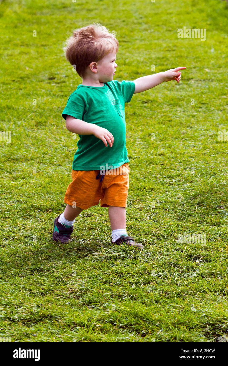 Young boy pointing and playing alone in a field Stock Photo - Alamy