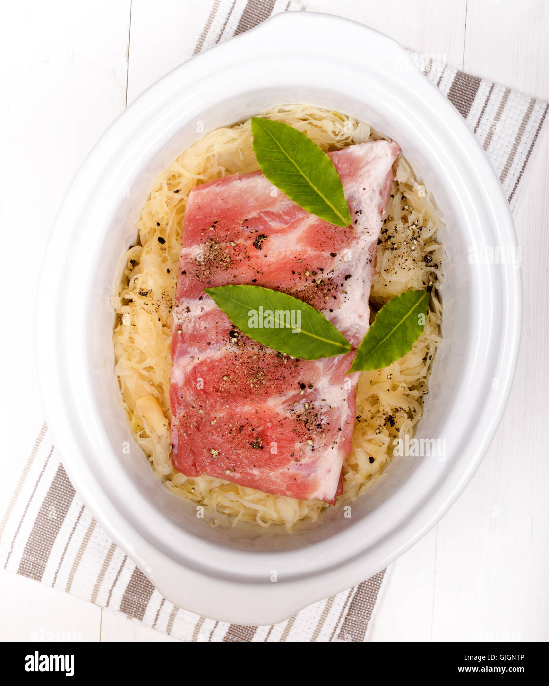 fresh sauerkraut and pork ribs with bay leaf in a white slow cooker Stock Photo