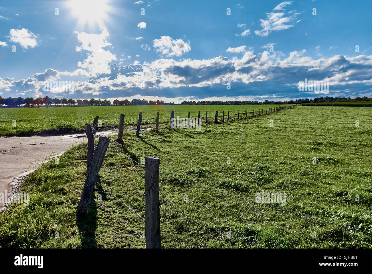 Fenced pastures right after a thunderstorm, with the sun breaking through in rural area, creating strong sun beams Stock Photo