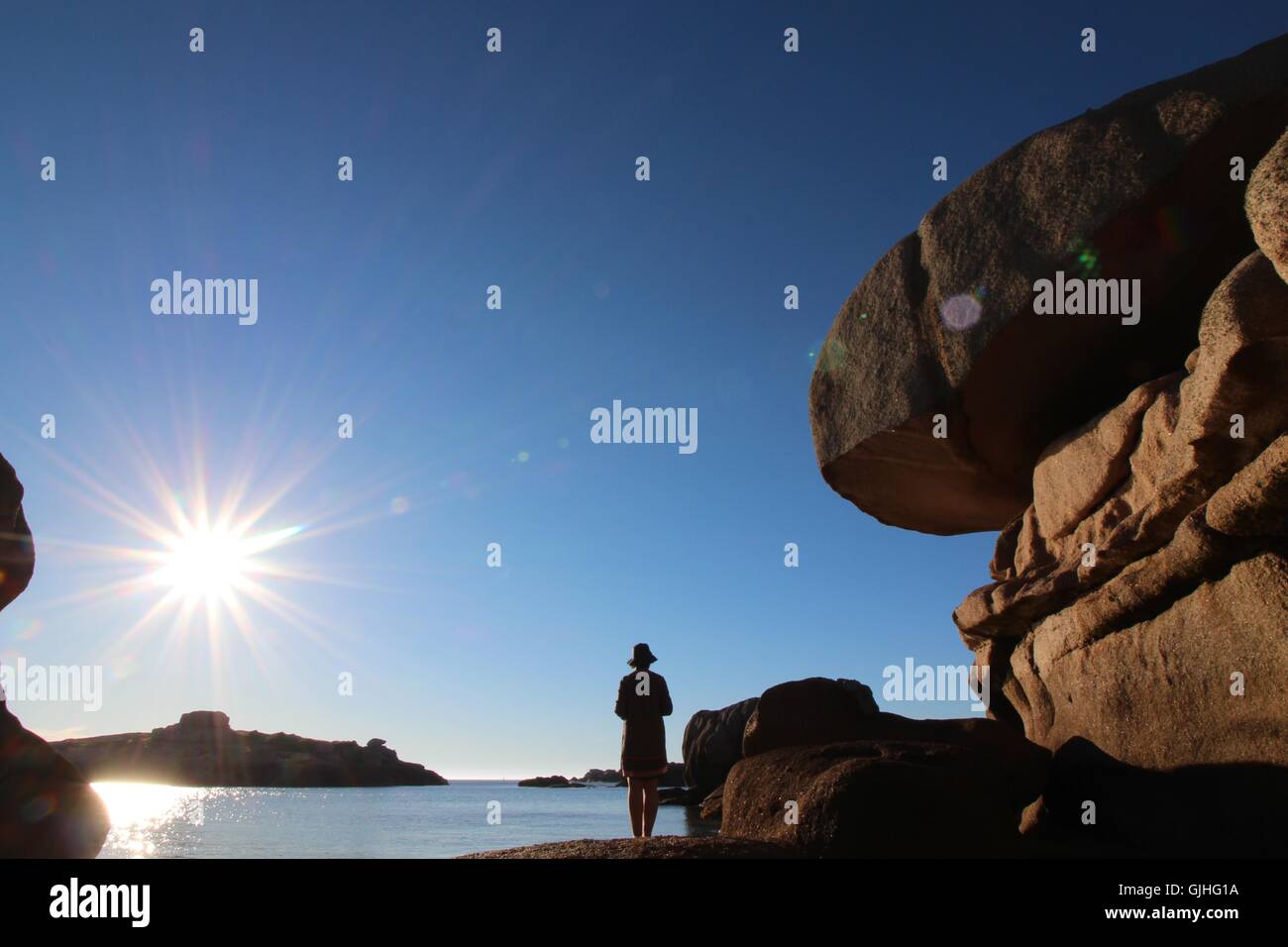 Woman standing on rocks on beach, Brittany, France Stock Photo