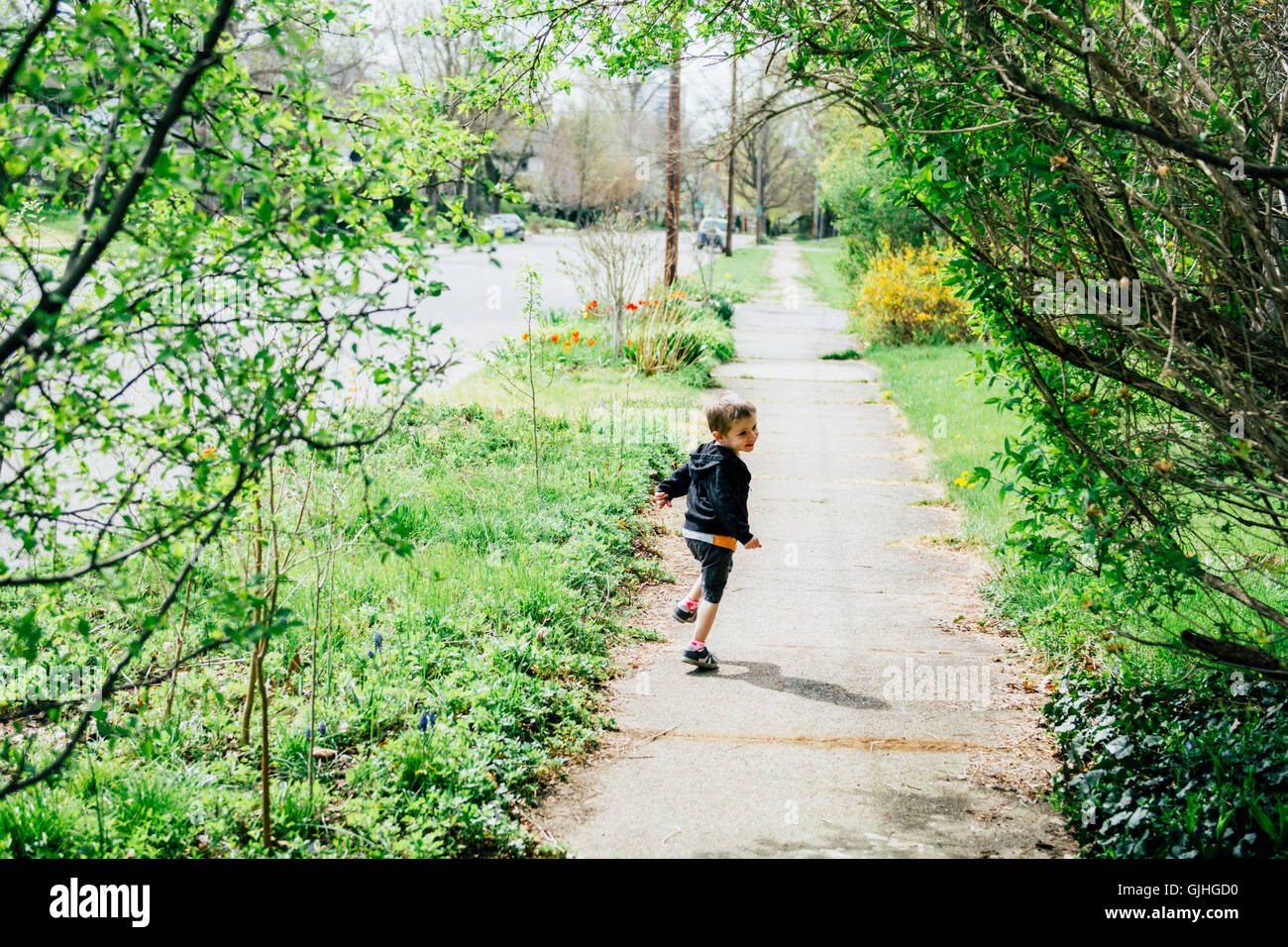 Boy running along pavement looking over his shoulder Stock Photo