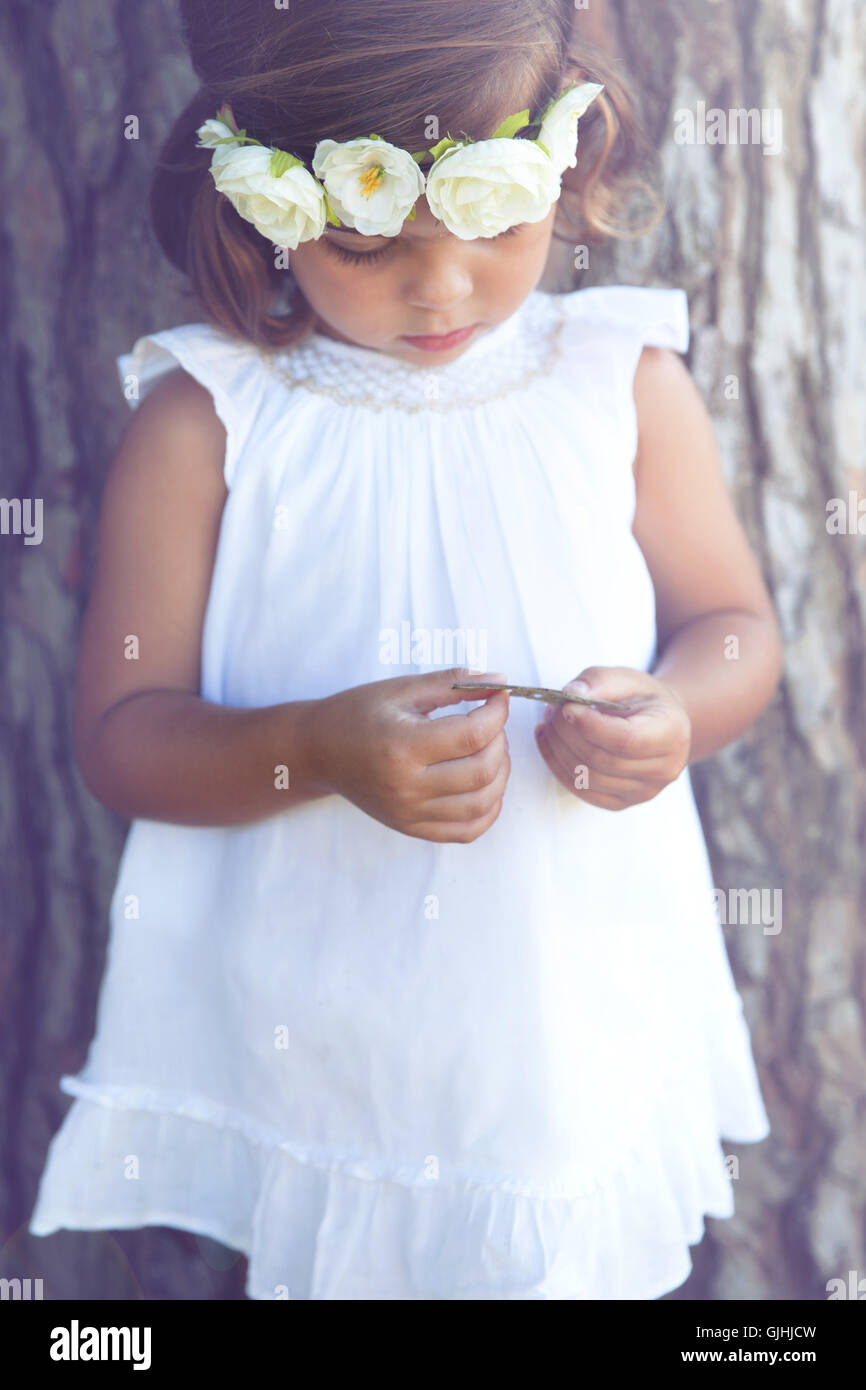 Portrait of a girl standing by tree wearing flower headdress Stock Photo