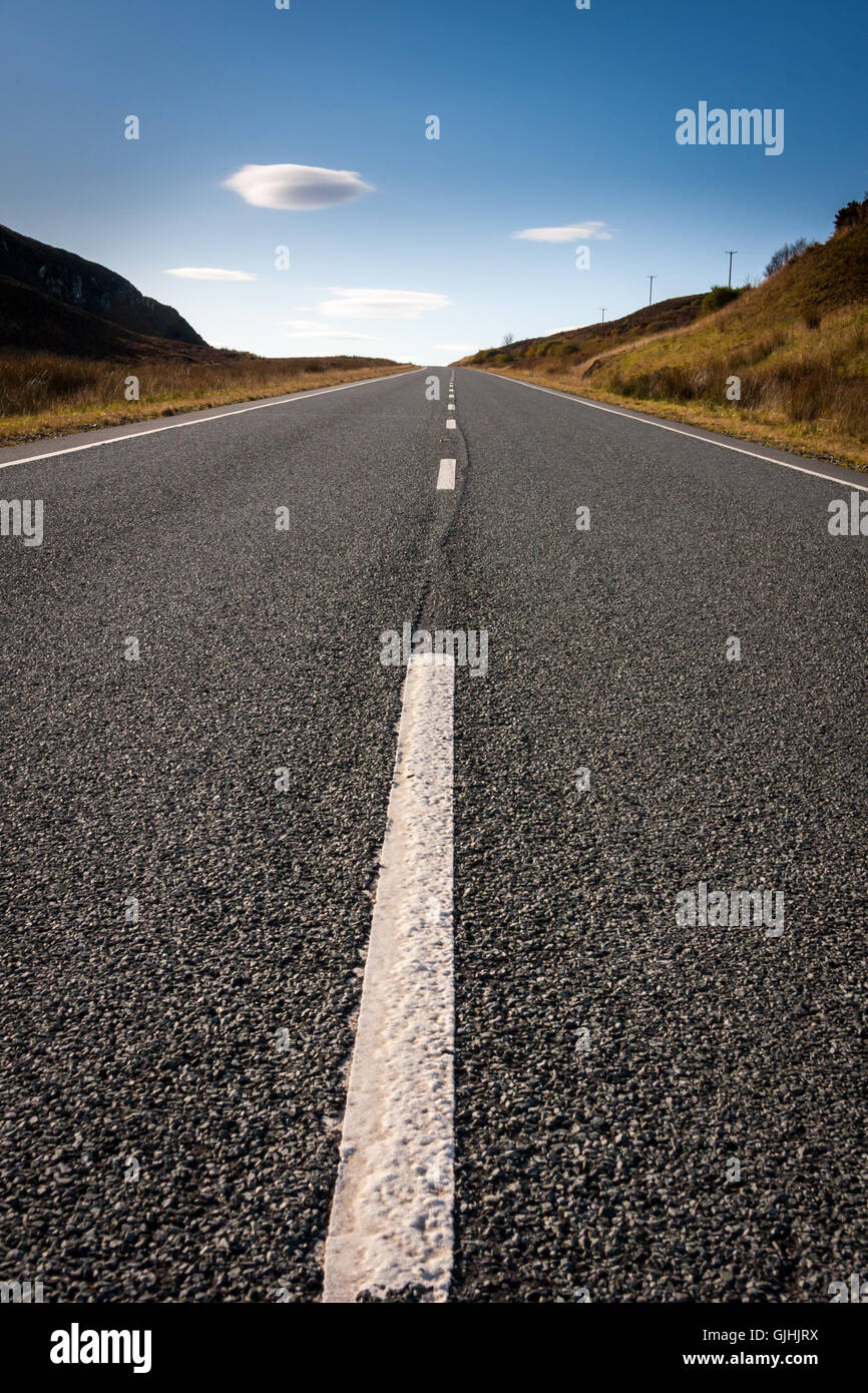 A road leading from the viewer to the horizon with small clouds in the ...