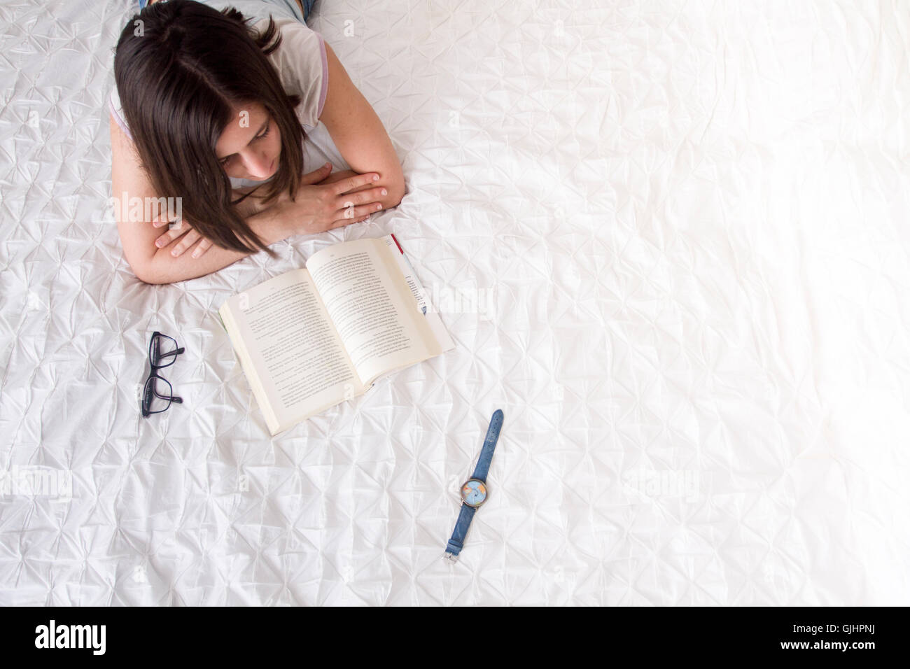 Girl reading a book on her bed Stock Photo