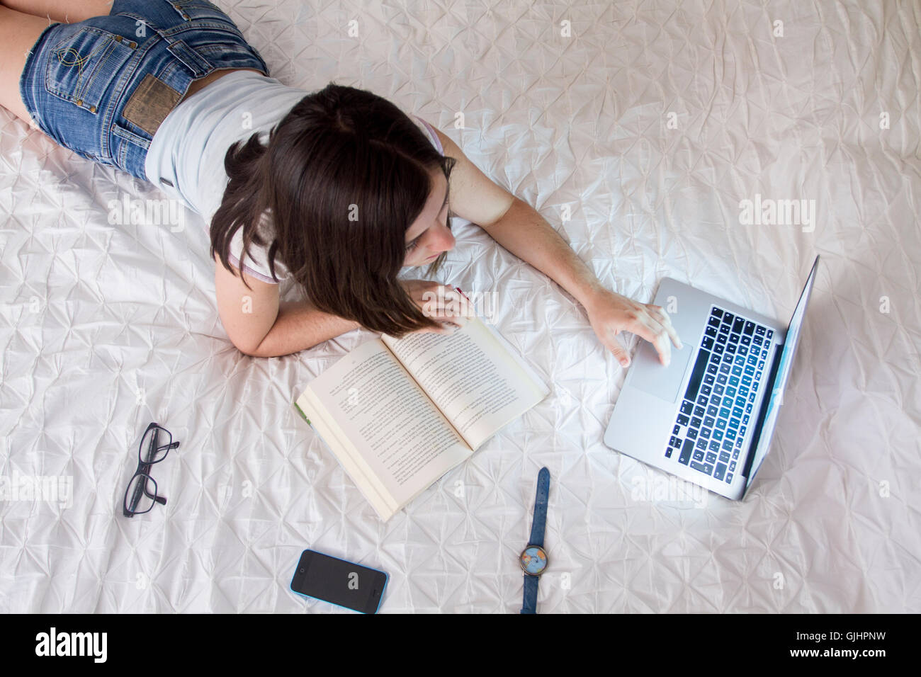 Girl reading a book and surfing the net Stock Photo