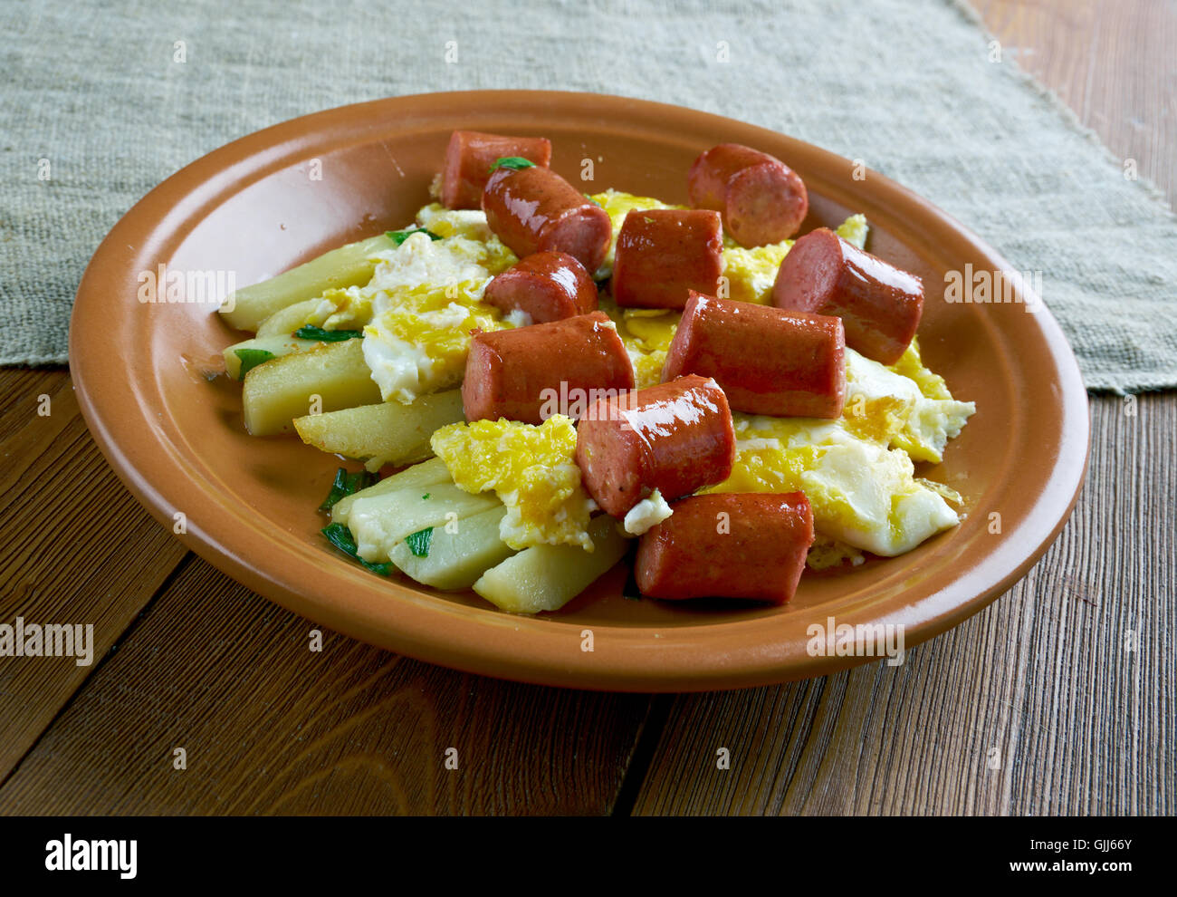 Huevos rotos con chistorra.scrambled eggs with sausage and potatoes. Mexican style. Stock Photo