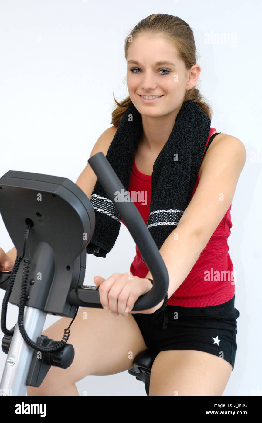 young woman on bicycle ergometer Stock Photo