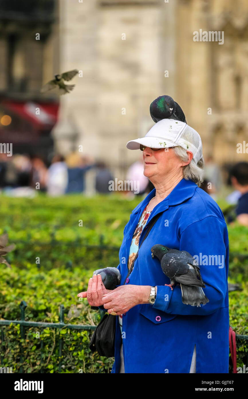 Woman in Paris with birds on her head and arm. Stock Photo