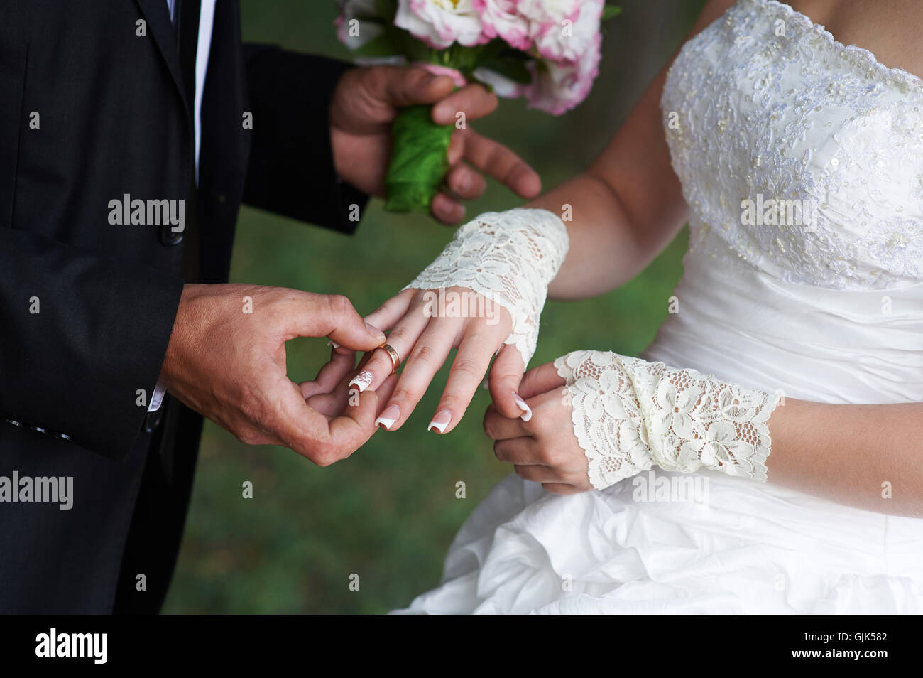 groom embraces bride, and she holds a bridal bouquet in his hands Stock Photo