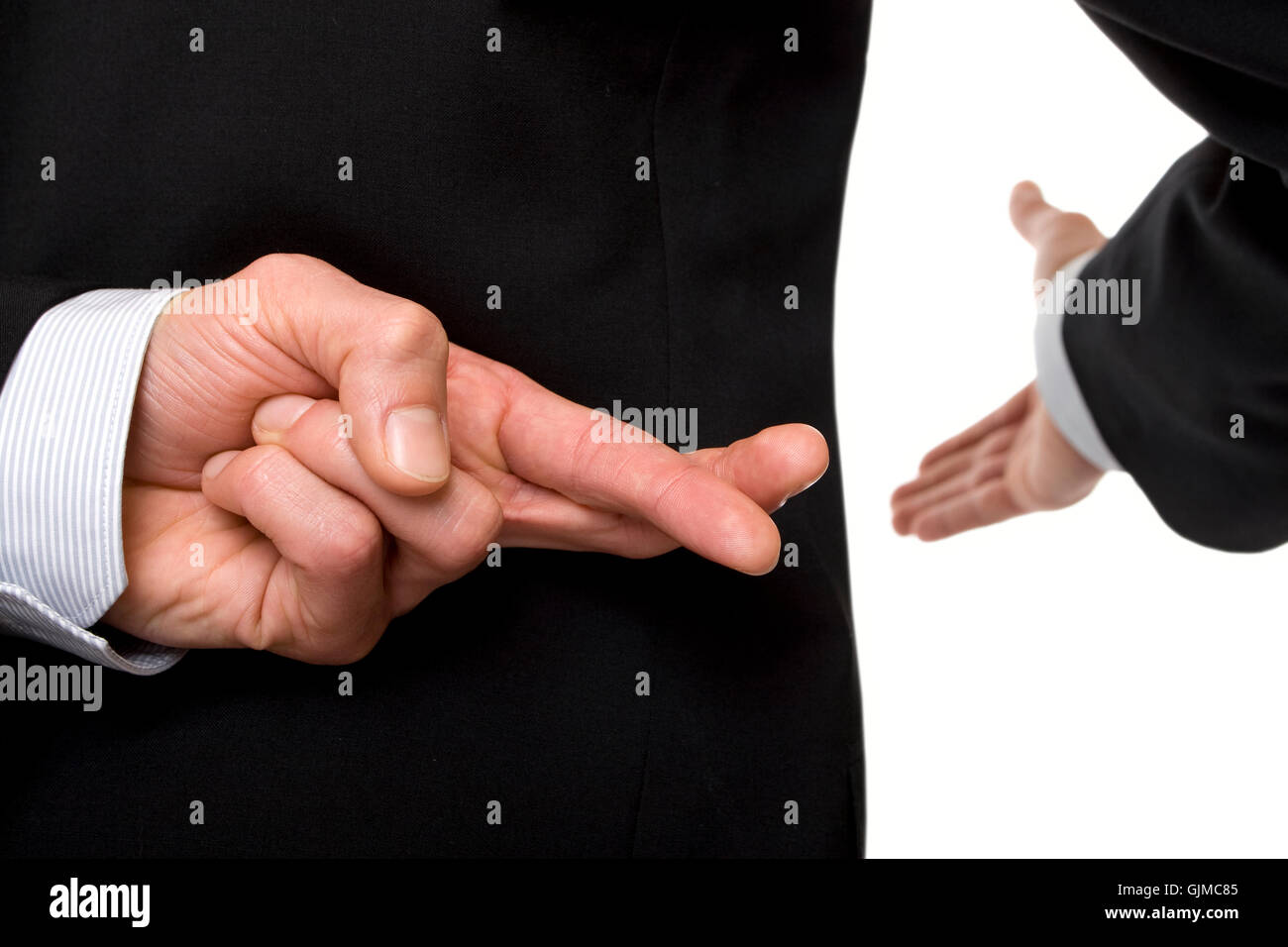 crossed fingers at handshake Stock Photo