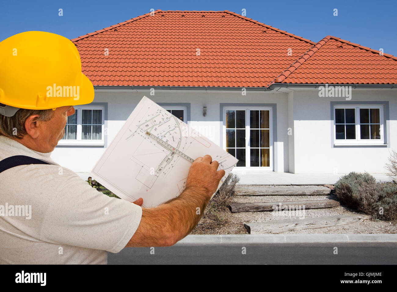construction worker with plan in front of house Stock Photo - Alamy