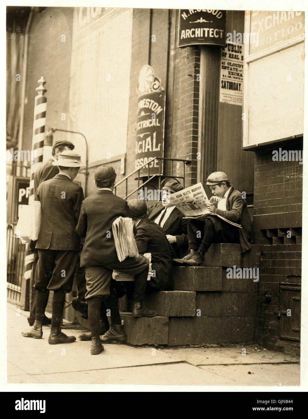 This iconic photograph by Lewis Hine shows a group of newsboys sitting ...