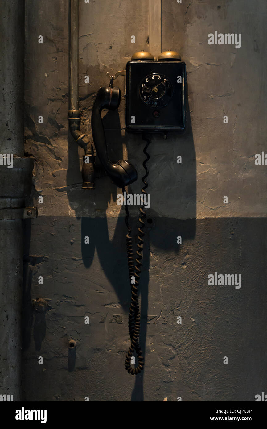 An old black telephone hanging on the wall inside a workshop Stock Photo