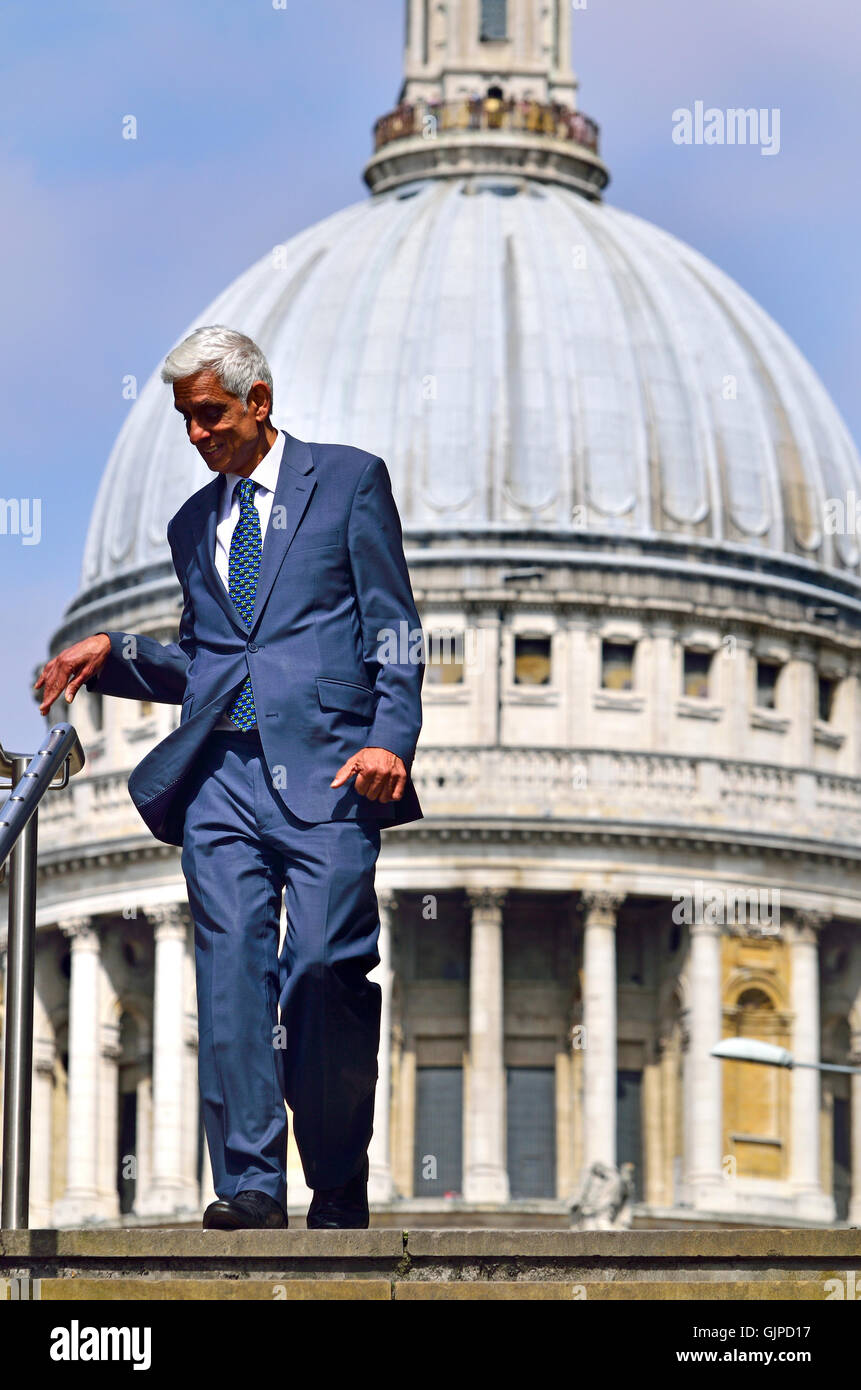 London England, UK. Indian businessman walking down the steps of the Millennium Bridge, St Paul's Cathedral behind Stock Photo