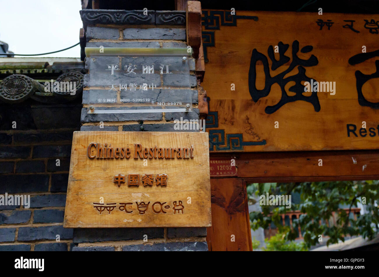 A restaurant sign written in English, Chinese and Geba (traditional Naxi) languages, Old Town, Lijiang, Yunnan, China. Stock Photo