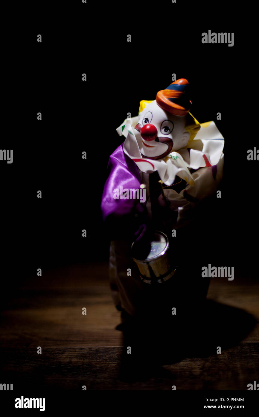 A vintage musical wind up clown toy that is standing alone on a wooden floor. Stock Photo