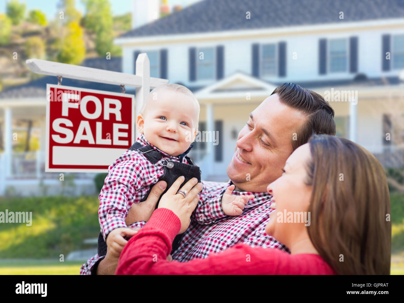 Happy Young Family In Front of For Sale Real Estate Sign and House ...