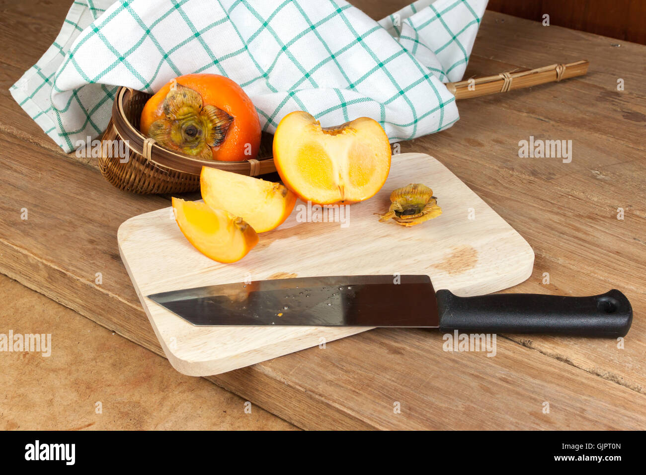 Persimmon yellow color ripe split fruits on wood table Stock Photo