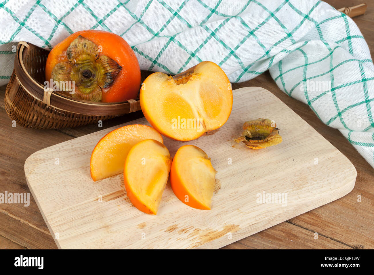 Persimmon yellow color ripe split fruits on wood table Stock Photo