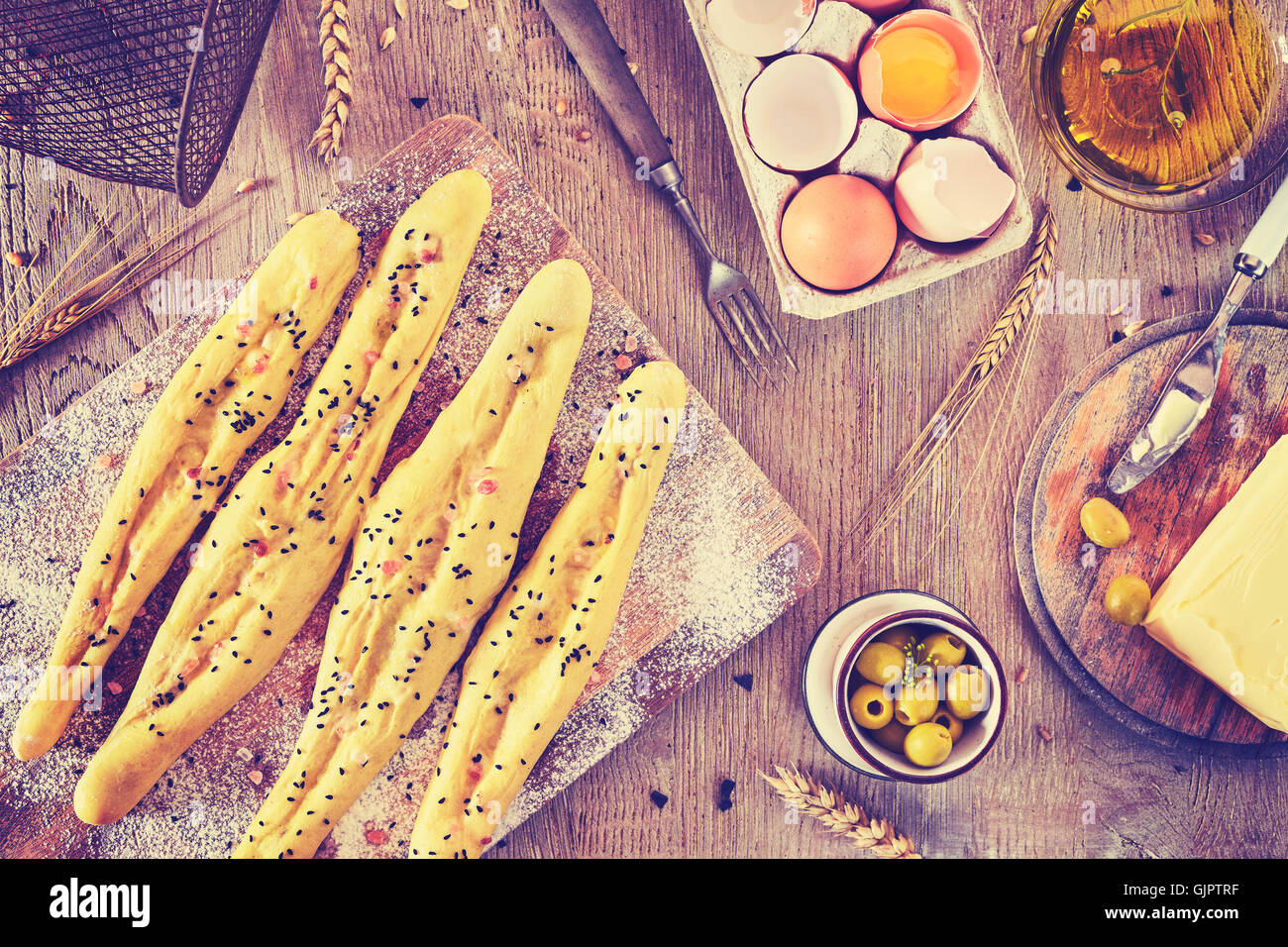 Vintage toned bread sticks ready for baking, rustic setting on a wooden table. Stock Photo