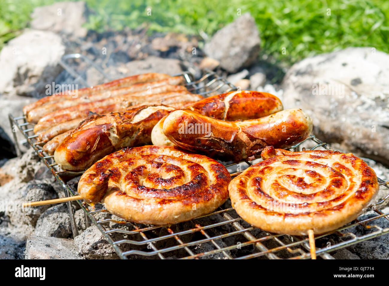 Grilling bratwursts on a charcoal grill Stock Photo