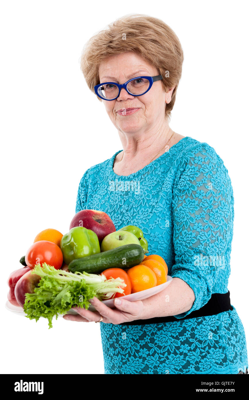 Mature happy woman holding a tray with fruits and vegetables in hands ...