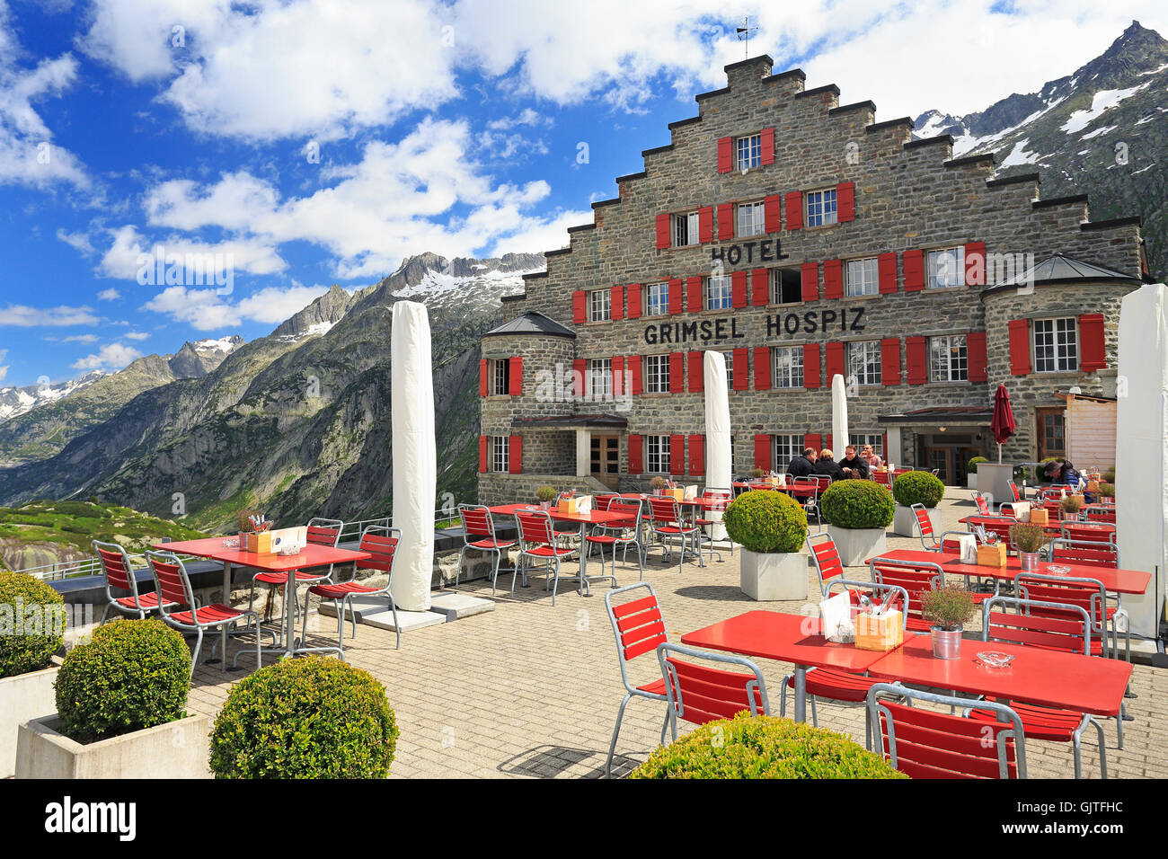 Tourists enjoying lunch on Grimsel Hotel terrace in Switzerland Alps Stock Photo