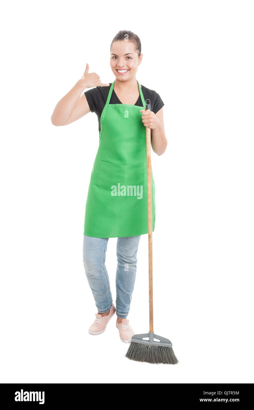 Joyful cleaning girl with apron doing a call gesture while cleaning the house isolated on white background Stock Photo