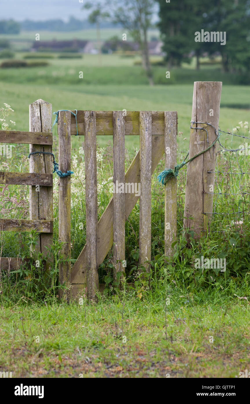 An old wooden gate in a field kept closed with old rope Stock Photo